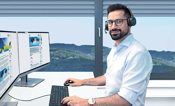 Büroangestellter mit Headset an einem PC-Arbeitsplatz