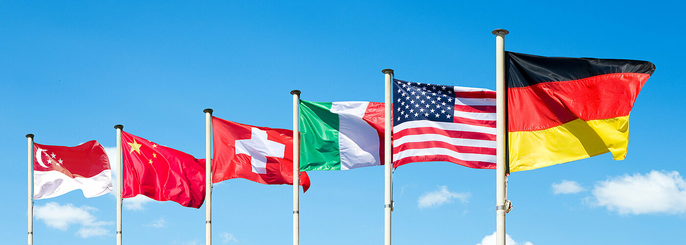 Flaggen im Wind der Länder Singapur, China, Schweiz, Italien, USA und Deutschland