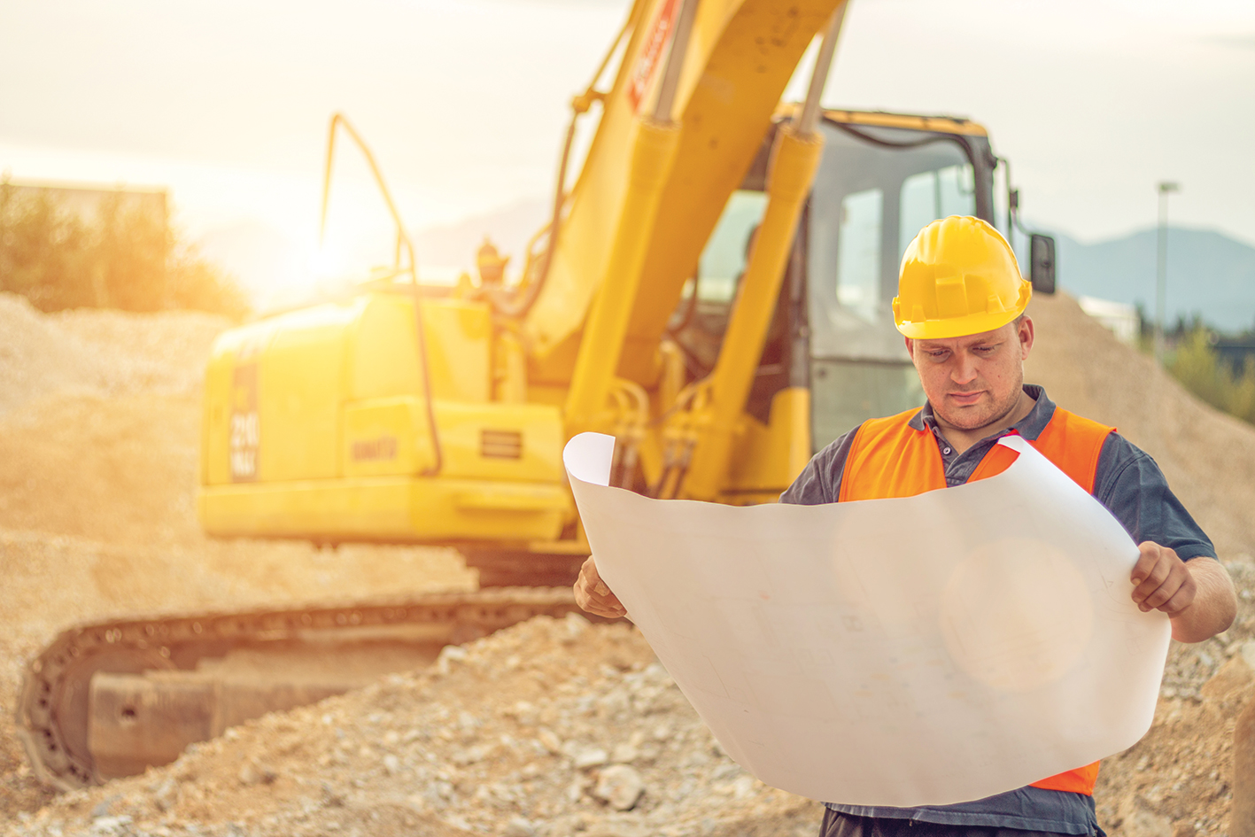 Chef de chantier avec une excavatrice en arrière-plan